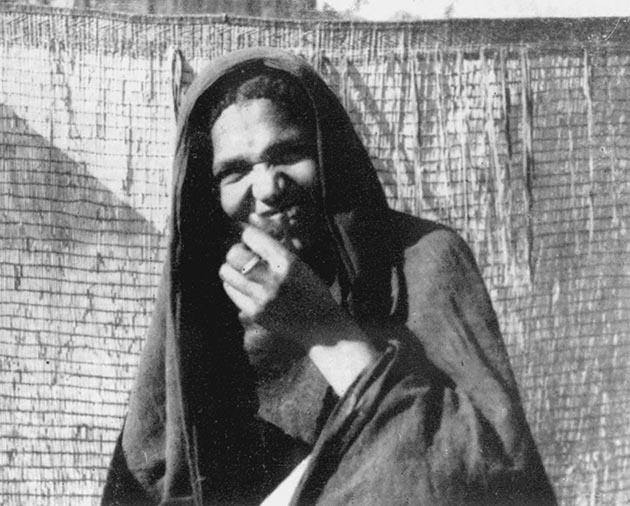 Νεαρή Tuareg πλένει τα δόντια της με ραβδί. Πίσω φαίνεται το καλαμένιο κάλυπτρο γύρω από τη σκηνή που λέγεται “asaber”.