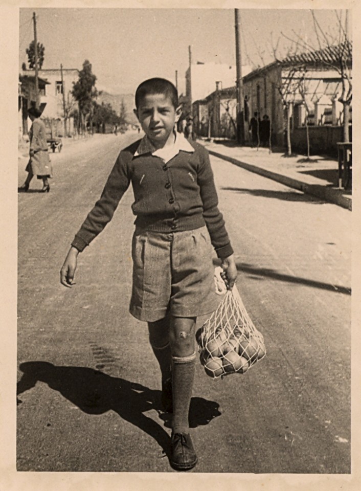 Ο μικρός Ιωάννης Περικλάκης το  1953, επιστρέφοντας από τη Βαρβάκειο Αγορά, επί της οδού Βασιλέως Κωνσταντίνου που μετονομάστηκε οδός Δημαρχείου (Δωρεά Αθηνά Δασκαλάκη - Αρχείο του Ιωάννη Περικλάκη Δόλωμα) 