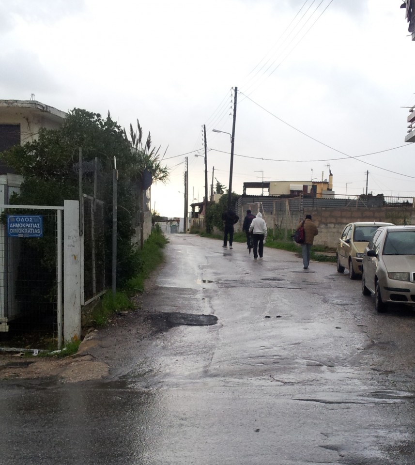 Χρήστες που μόλις έχουν κατέβει από το λεωφορείο και περπατούν στην οδό Βαρδουσίων. Στο τέλος του δρόμου τους περιμένει ο έμπορος ουσιών.