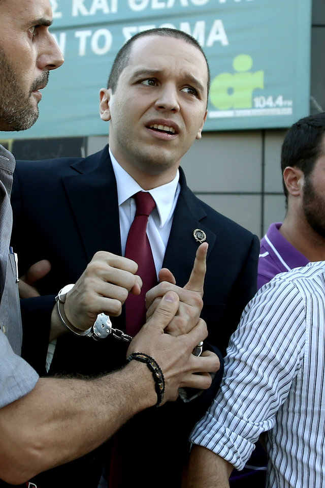 Ο Ηλίας Κασιδιάρης μεταφέρεται με χειροπέδες για να ορκιστεί ως νεοεκλεγέν μέλος του Δημοτικού Συμβουλίου του Δήμου Αθηναίων, την 29η Αυγούστου 2014.