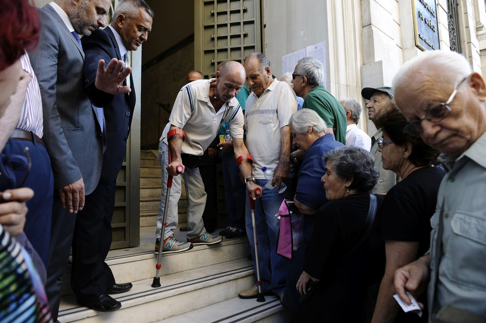 Συνταξιούχοι έξω από το κατάστημα της Εθνικής Τράπεζας στην Ομόνοια περιμένουν στην ουρά για να πάρουν 120 ευρώ από τη σύνταξή τους.