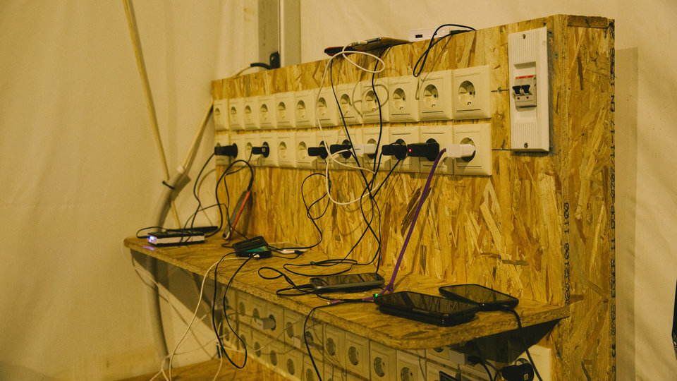 Πρόσφυγες φορτίζουν τα κινητά τους σε σκηνή, στον καταυλισμό της Ειδομένης.