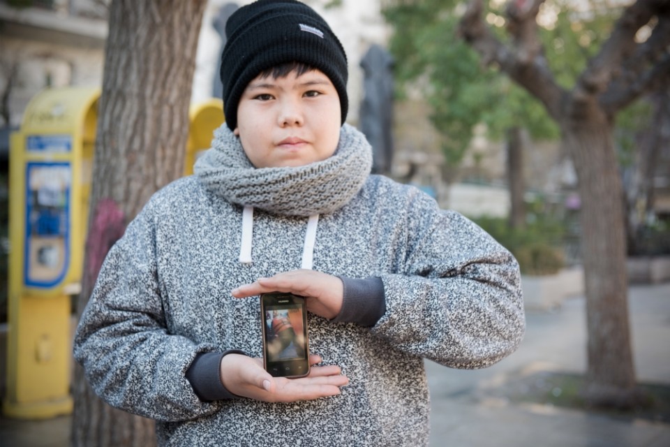 Φεβρουάριος 2016: Αγόρι στην Πλατεία Βικτωρίας δείχνει φωτογραφίες στο κινητό του από το θαλάσσιο πέρασμα με τη βάρκα. © Georgios Makkas