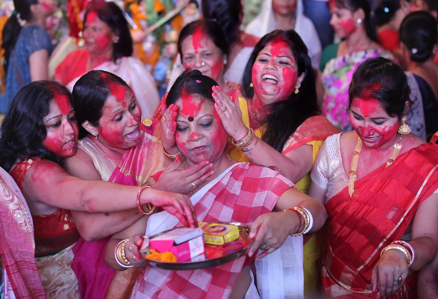 Ινδές της κοινότητας Μπενγκάλι βάζουν μια κατακόκκινη μπογιά η μια στο πρόσωπο της άλλης, καθώς λαμβάνουν μέρος στο «Sindoor Puja», ένα τελετουργικό πριν από την εμβάπτιση της θεάς Durga σε υδάτινες μάζες την τελευταία ημέρα του Φεστιβάλ Durga Puja στο Νέο Δελχί. Αυτή η πράξη σηματοδοτεί το τέλος του Φεστιβάλ. PHOTO: RAJAT GUPTA