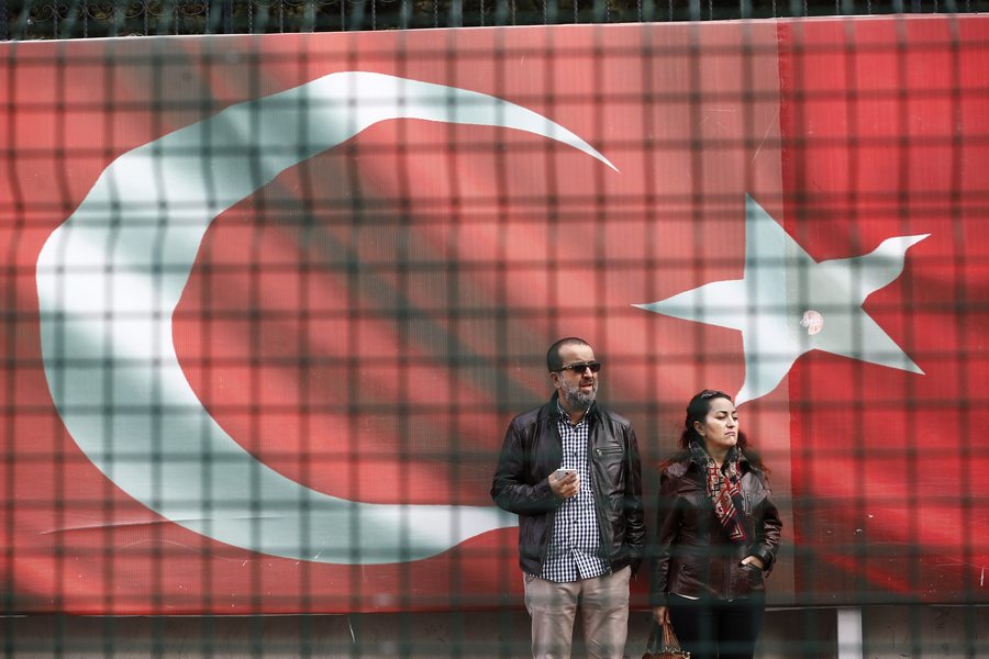 epa05611064 People stand by a giant Turkish flag in front of the headquarter of Cumhuriyet daily newspaper in Istanbul, Turkey 31 October 2016. Turkish police detained the editor-in-chief Murat Sabuncu, columnist Hikmet Cetinkaya of the opposition newspaper Cumhuriyet in Istanbul and 13 arrest warrants have been issued for journalists and executives during an police operation.  EPA/SEDAT SUNA