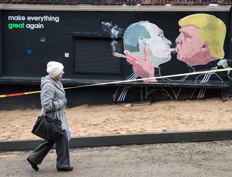 epaselect epa05640793 A picture made available on 21 November 2016 shows a woman passing by a graffiti mural depicting US President-elect Donald Trump (R) smoking with Russian President Vladimir Putin on the wall of the barbecue restaurant Keule Ruke in Vilnius, Lithuania, 20 November 2016.  EPA/ROMAN PILIPEY