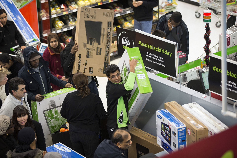 An employee, surrounded by customers, carries a new Toshiba Corp. flat screen television during a Black Friday discount sale inside an Asda supermarket in Wembley, London, U.K., on Friday, Nov. 29, 2013. Britons queued outside Asda supermarkets this morning and charged into stores when doors opened at 8 a.m. as the U.K. grocery chain took on the Black Friday mantle from U.S. owner Wal-Mart Stores Inc. Photographer: Simon Dawson/Bloomberg