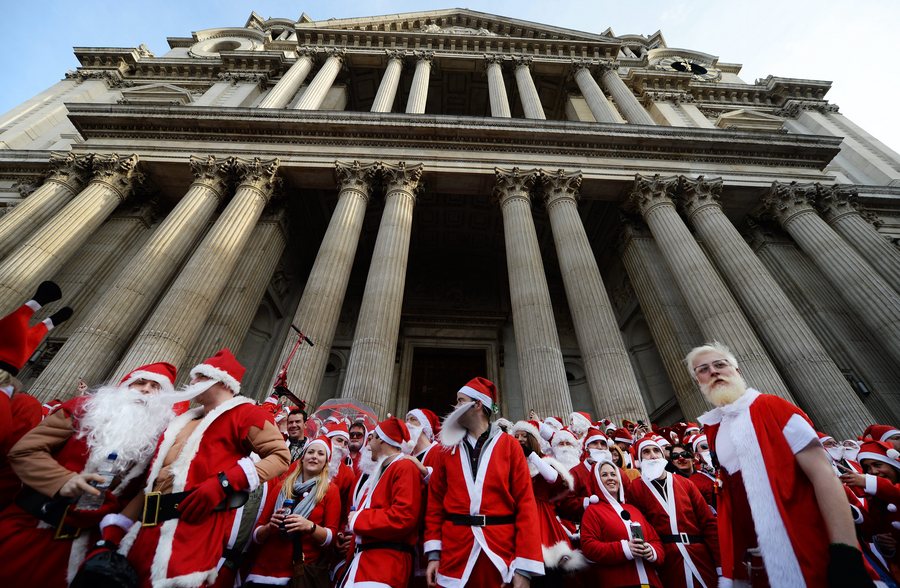 epa03990454 Hundreds of Christmas revellers gather outside St.Paul's Cathedral during the Santacon celebration in London, Britain, 14 December 2013. SantaCon is an annual mass gathering of people dressed in Santa Claus costumes parading publicly on streets and in bars in cities around the globe. EPA/ANDY RAIN