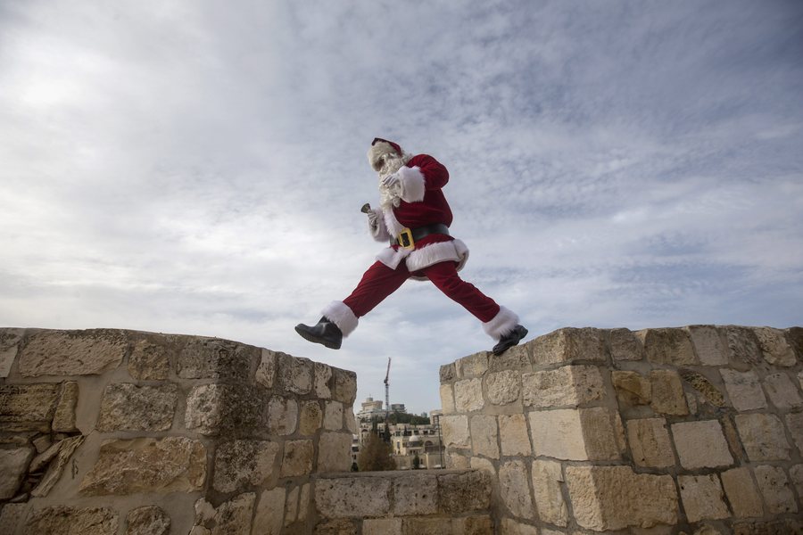 epa05686541 A man wearing a Santa Claus costume walks on the wall of the Old City of Jerusalem, Israel, 23 December 2016, ahead of the Christmas holidays.  EPA/ATEF SAFADI
