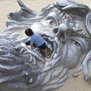 Ένα παιδί παίζει στο στόμα του αγάλματος με τίτλο «Awakening»