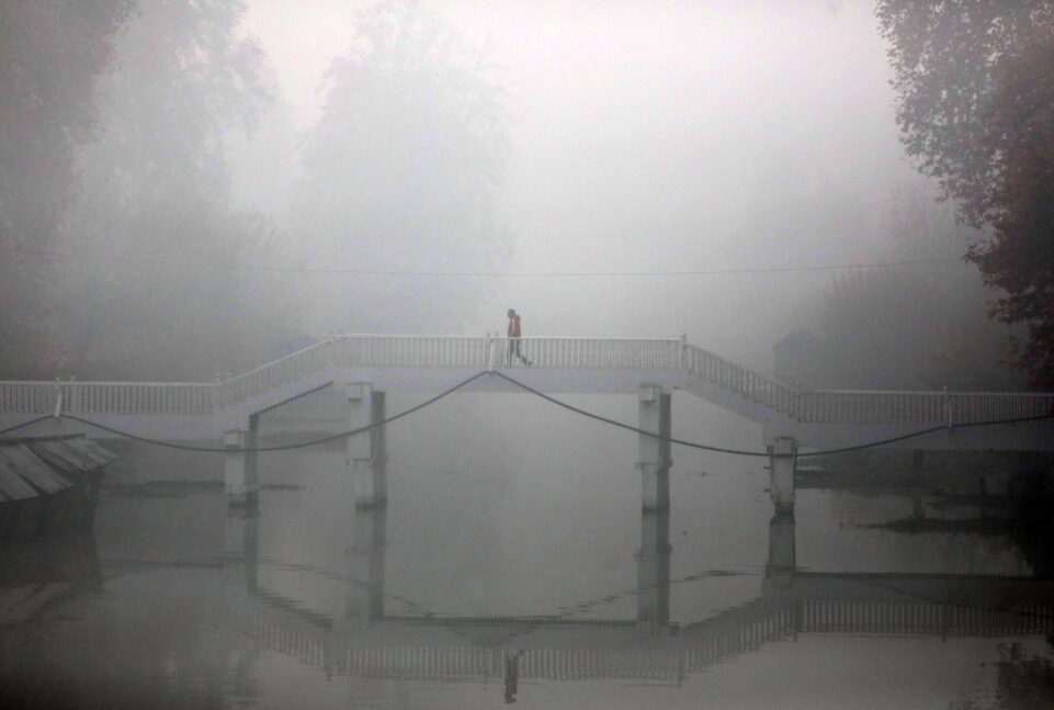 Μόνος άντρας περπατά σε ξύλινη γέφυρα, κρυμμένος από την ομίχλη ενός κρύου πρωινού στην Σριναγκάρ, την καλοκαιρινή πρωτεύουσα του Ινδικού Κασμίρ, 22 Νοεμβρίου 2023.