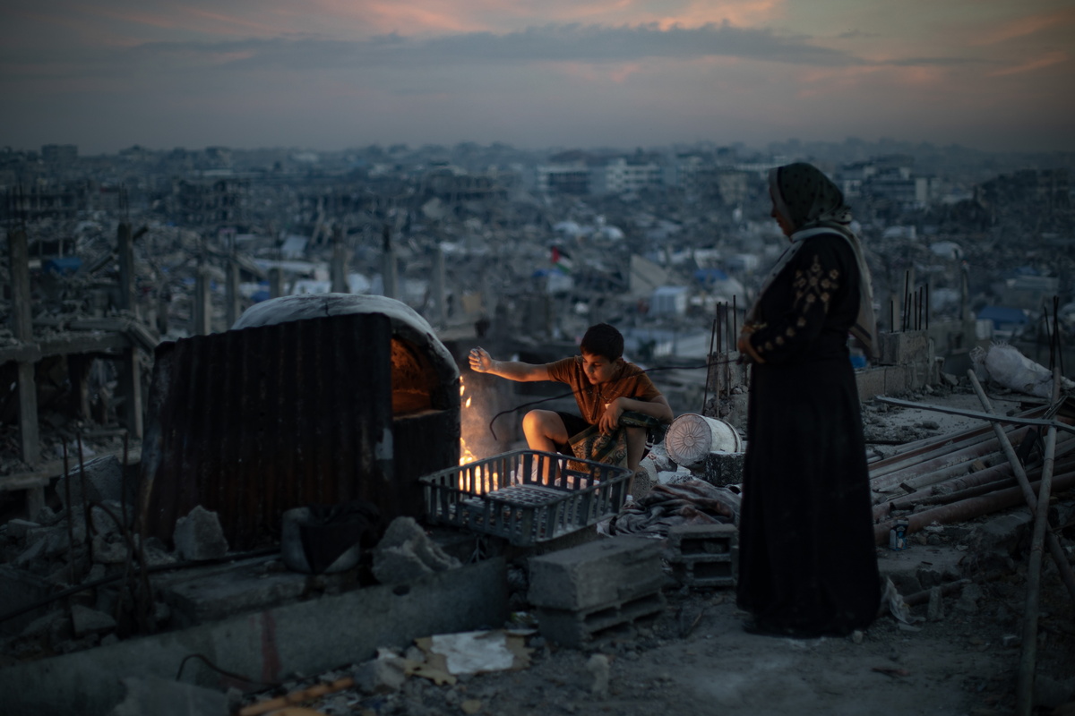 epa11970606 The Maarouf family prepares iftar over a fire in the rubble of their destroyed home during the holy month of Ramadan in Jabalia refugee camp, northern Gaza Strip, 17 March, 2025. EPA/HAITHAM IMAD